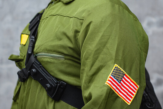 Security guard or law enforcement officer wearing tactical uniform with chest pouch and USA flag patch on dark background. Public safety, professional security services, patrol and emergency response.
