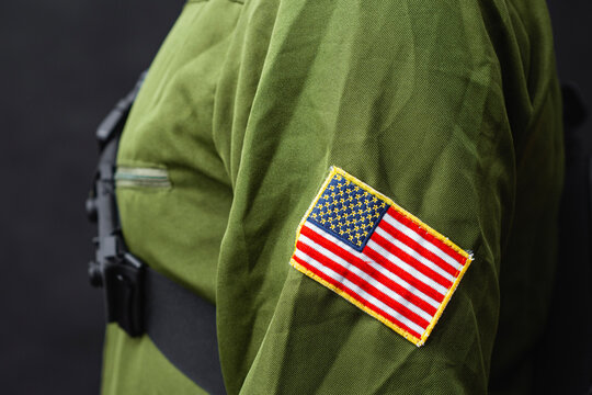Security guard or law enforcement officer wearing tactical uniform with chest pouch and USA flag patch on dark background. Public safety, professional security services, patrol and emergency response.