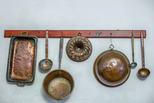 Vintage kitchen utensils hanging on wall in kitchen. Metal old kitchen appliances, baking molds, colander, ladles