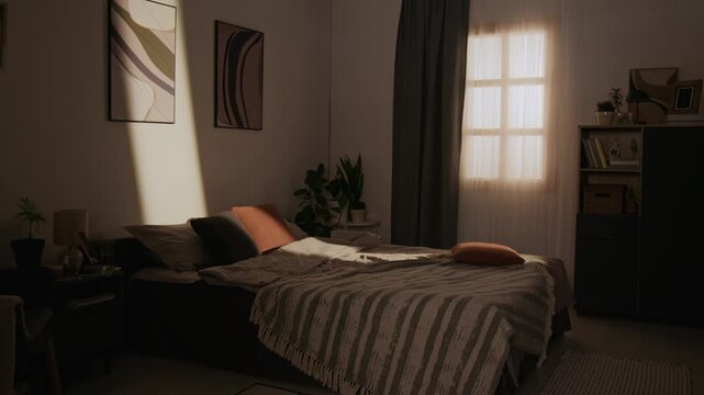 Warm sunlight streaming through window onto empty made bed in modern apartment bedroom. Video is perfect for real estate marketing, bedding brand commercials, or sleep health advertisements
