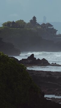 Stony Reef And Tanah Lot Temple Against Haze, Imagined Priest Conducting Quiet Ritual As Tide Sculpts Layered Rock, Steady Swell And Misty Horizon, Timeless Cultural Atmosphere With Muted Cinematic