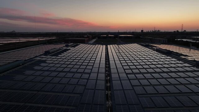 Solar panel arrays on industrial rooftops during twilight with sunset sky and distant horizon