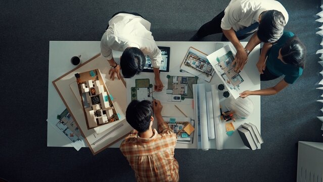 Top down view of smart architect engineer measure blueprint by using architectural equipment while group of designer talking about building design or house construction at meeting room. Alimentation.