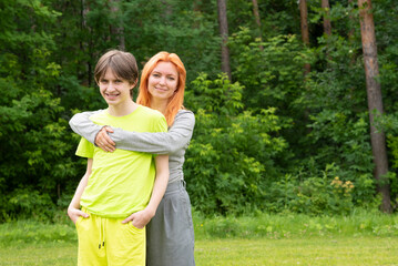 Fototapeta premium Happy mother hugging her teenage son in summer forest