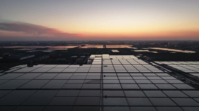Photovoltaic power station array at sunset with reflective water surfaces and geometric layout