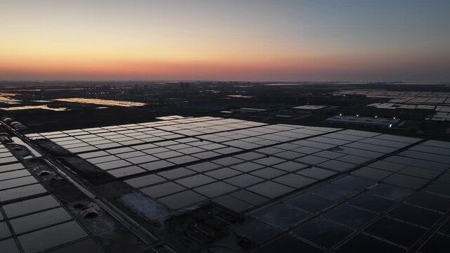 Salt evaporation ponds in grid pattern during sunset with reflective water surfaces
