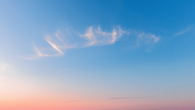 Beautiful sunset sky background with soft cirrus clouds. Pastel morning sky background banner with copy space representing freedom, inspiration and serenity.