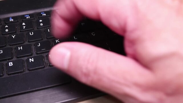 POV: a hand typing on a computer keyboard. A Bluetooth keyboard. A wireless keyboard. A dusty keyboard. Typing with only one hand. A dirty computer keyboard. Writing, close-up.