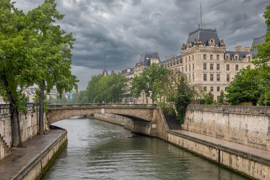 Captivating view of the Seine River in Paris, France, showcasing historic architecture and lush greenery under dramatic skies.