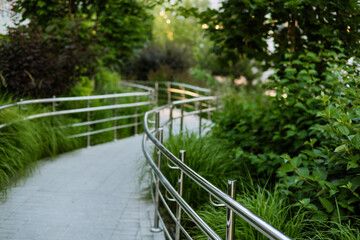 Fototapeta premium Curving landscaped pedestrian pathway with ornamental grasses and lush greenery showcasing contemporary urban landscape architecture and sustainable Green space for sustainable and clear urban living.