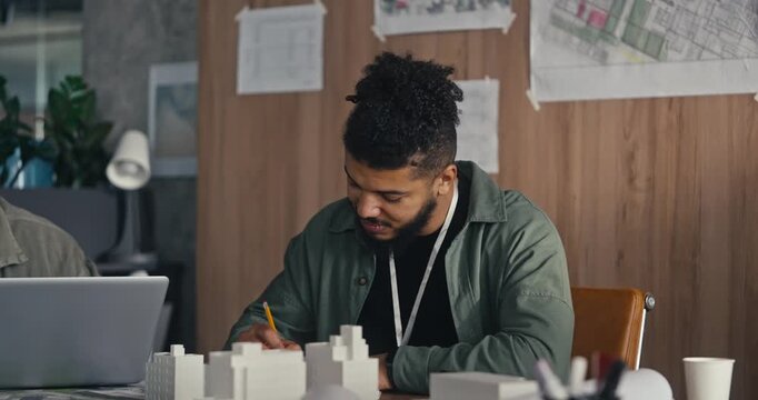 A person is focused on drawing designs while collaborating in an urban planning office during midday hours