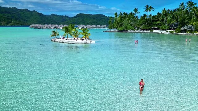 Woman walking in crystal clear bora bora lagoon