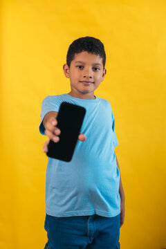 Child showing smartphone on yellow background
