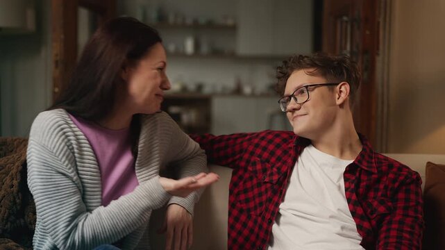 Cheerful teen boy and his mother talking and laughing together, warm family bond