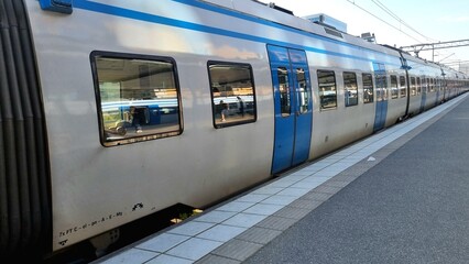 High-speed electric intercity train that runs between cities. Platform at Solna station with long intercity commuter train with gray cars and blue doors. Travel and journey in Sweden  © Nataliia Ivashchenko