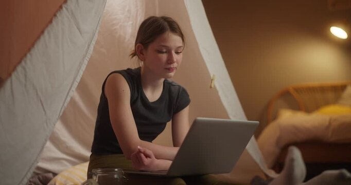 Young woman working on a laptop inside an indoor tent
