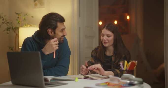 Smiling man and woman discussing notes at a laptop in a cozy home interior