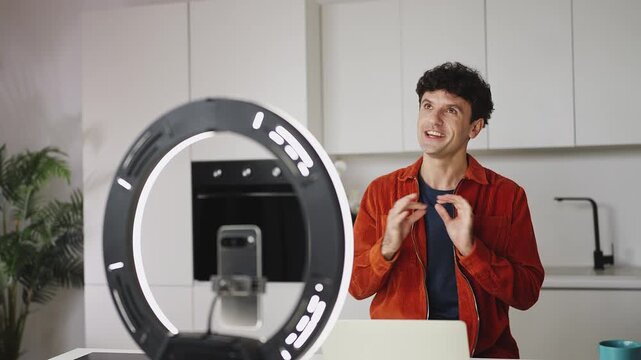 Happy man recording lifestyle vlog on smartphone at home, influencer concept