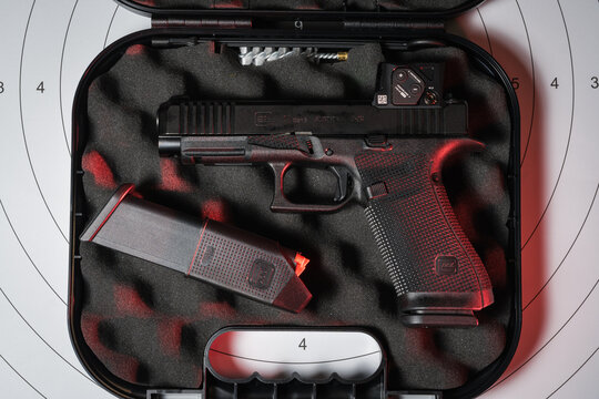 BALTIC STATES - JUNE 29, 2026: An unboxed Glock 17 Gen 6 semi-automatic pistol with an Aimpoint COA red dot sight inside its original hard plastic case with a spare magazine.
