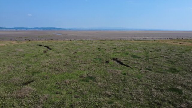 Low flying drone shot of the marsh grass at Grange over Sands in Cumbria showing the environment typical of Morecambe Bay