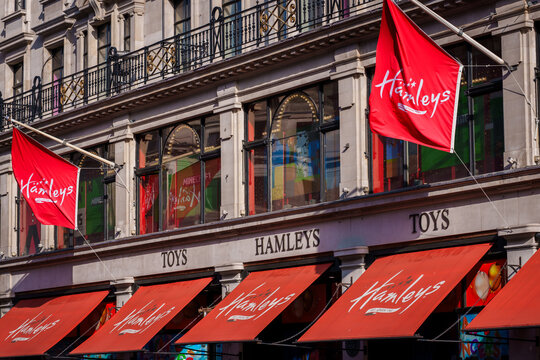 LONDON, UK. 16th  February 2025. The iconic red logo flag of Hamleys toy shop, established in 1760, hanging on the classic stone exterior of their boutique store in London's West End.