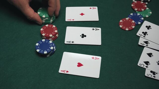 Close-up of poker game showing hands placing chips on table with playing cards face up, highlighting the action of betting in a competitive setting