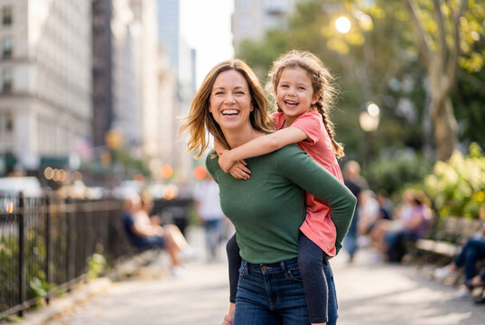 Cheerful mother giving her daughter a piggyback ride