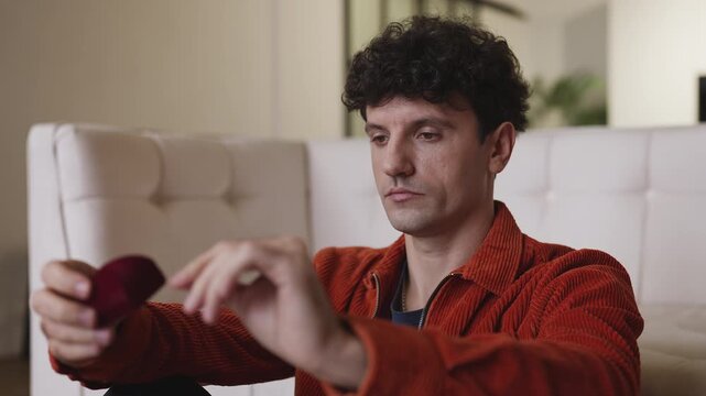 Pensive young man holding engagement ring, thinking about proposing marriage
