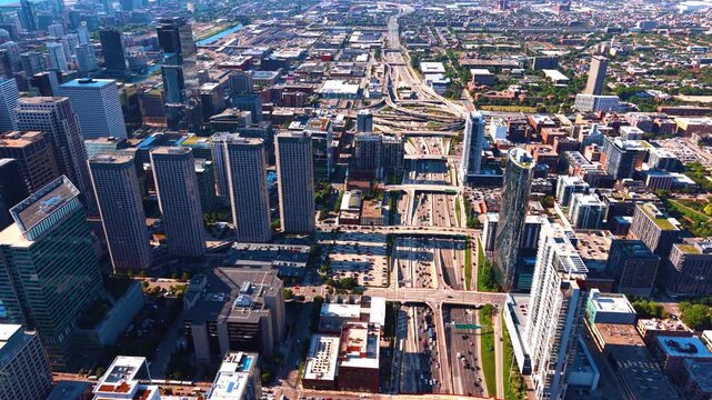Kennedy Expressway flowing directly through the West Loop area of downtown Chicago. Jane Byrne Interchange in the backdrop. Multiple cars move by the city center at daytime. Aerial view.