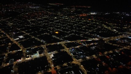 Fototapeta premium Aerial view of a city at night with illuminated streets and buildings creating a grid pattern