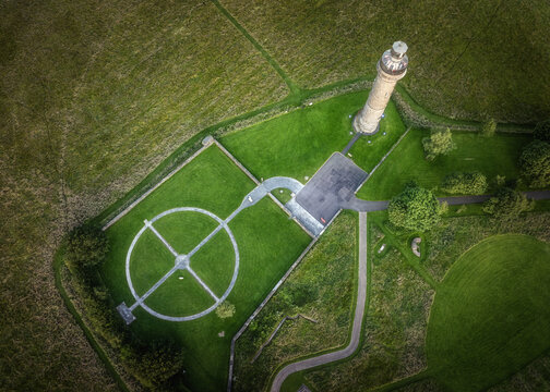 Aerial view of Spire of Lloyd surrounded by lush green fields and a circular stone path in County Meath, Ireland.