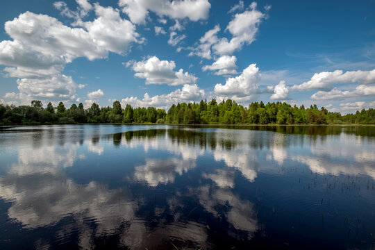 Scenic landscape of a calm lake in Karelia, Russia, with beautiful cumulus clouds reflecting in the mirror water