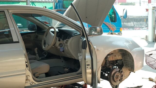 Car under repair in garage. Hood open, front wheel removed. Interior visible. Tools scattered. Work in progress. Ideal for automotive repair, DIY projects, or workshop scenes. No people shown