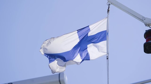 Finnish flag waving on ship mast against clear blue sky