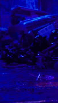 Trash is scattered across the ground in a dark location. A faint purple light illuminates the scene, showing various discarded items. The atmosphere suggests neglect and disorder.