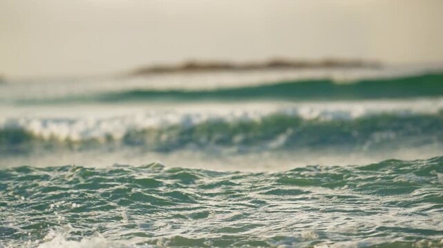 Foamy green ocean surface with blurred breaking wave and island horizon
