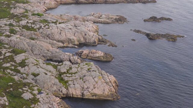 Aerial view of rugged rocky Nordic coastline with calm blue sea