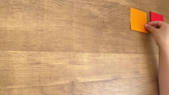Child Hand Places an Orange Origami Square Beside a Red One in a Regular Grid, 4K