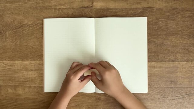 Child Hands Peel a Yellow Sticky Note and Stick It on an Open Notebook, 4K