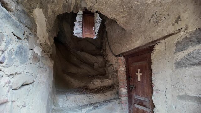 David Gareji complex showing an ancient rock-hewn Orthodox monastery in Georgia, featuring a weathered wooden door with a cross and rough stone walls carved into the mountain during the Middle Ages