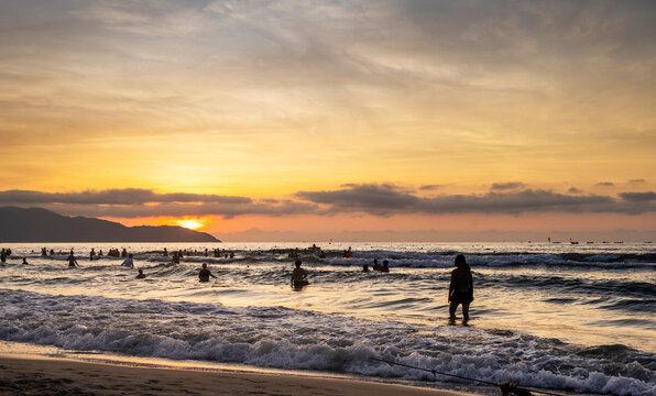 People relax and bathe,on Da Nang Beach at sunset,along the central coast of Vietnam.