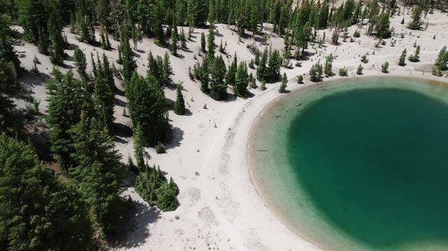 Sunny Summer Drone Flight Over Turquoise Mountain Lake with Snow and Pine Trees