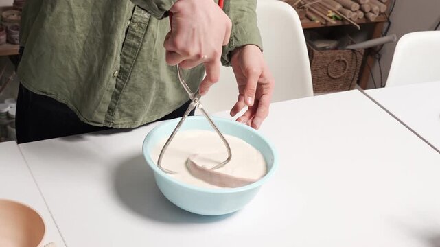Artisan Dipping Ceramic Bowl into Glaze Basin 4K Video. Artisan handles an unglazed clay vessel during the manual glazing process