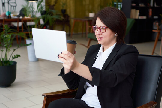 Young businesswoman having video call with tablet during cofe break