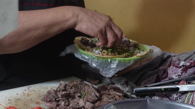 Close-up of hands preparing fresh street tacos with meat, onion and cilantro