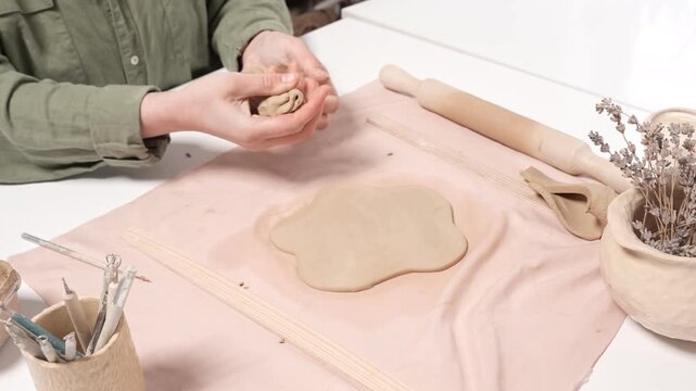 4k video of an artisan kneading raw clay by hand in a studio. This close-up footage captures the manual technique of wedging clay to prepare the material for pottery production and shaping