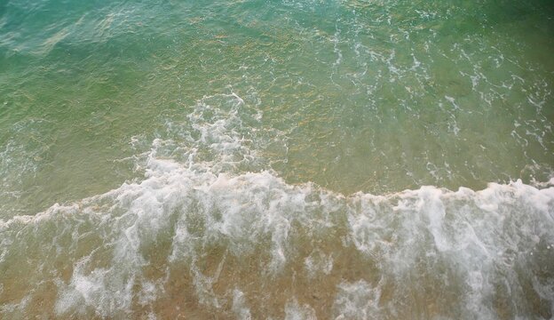 Turquoise sea surface with crushing waves and foam colorful water ariel shot summer sea background