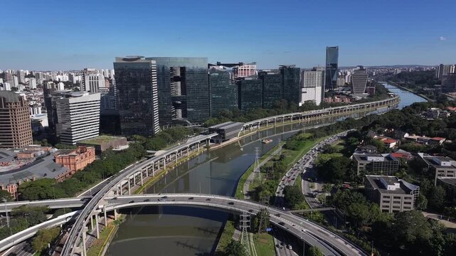 Aerial view of S&atilde;o Paulo business district along the Pinheiros River with modern skyscrapers, metro line, highways and urban infrastructure.
