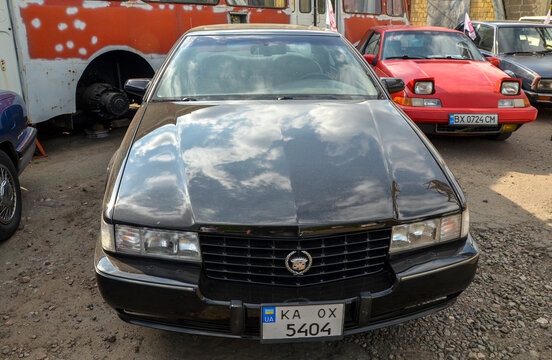 Classic glossy black Cadillac Seville STS luxury sedan, an iconic symbol of American automotive dominance, showcasing its timeless design and commanding presence