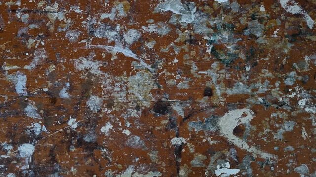 Distressed paint splatter texture with peeling layers on weathered brown surface